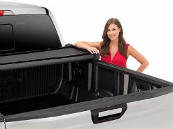 A woman stands next to a truck with a rolled up tonneau cover.